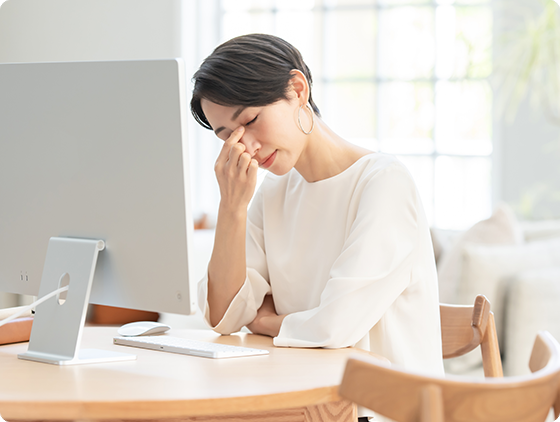 目の疲れを感じている女性が目頭を指で押さえている
